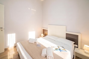 Habitació d'hotel amb llit, una vetustàt, una làmpada i una porta.