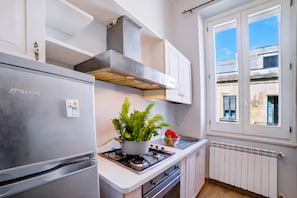 Eine moderne Küche mit eingebautem Gasherd, einem Edelstahlkühlschrank und weißen Schränken.