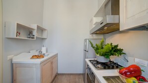A kitchen with white cabinets, a stove, and a bowl of peppers. - Archi Home - Apartment with Balcony in Central Lecce, Lecce, Italy (Lecce)