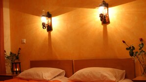 Une chambre d’hôtel avec une tête de lit en bois, deux lampes de chevet, un lit avec des oreillers blancs et un vase de fleurs posé sur la table de chevet.