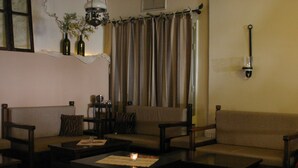 Un salon comprenant un canapé, des fauteuils, une table basse et une lampe.