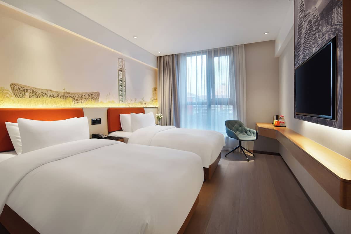 Une chambre d’hôtel avec deux lits, une télévision, un bureau et une chaise.