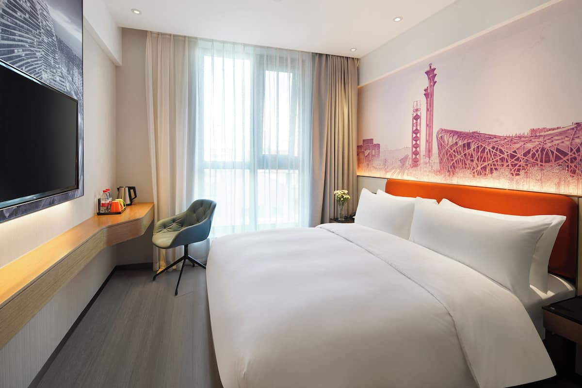 Une chambre d’hôtel avec un grand lit, une télévision, un bureau et une chaise.