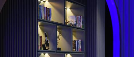 A modern bookshelf with books and decorative items, set in a room with a curved ceiling and blue lighting.