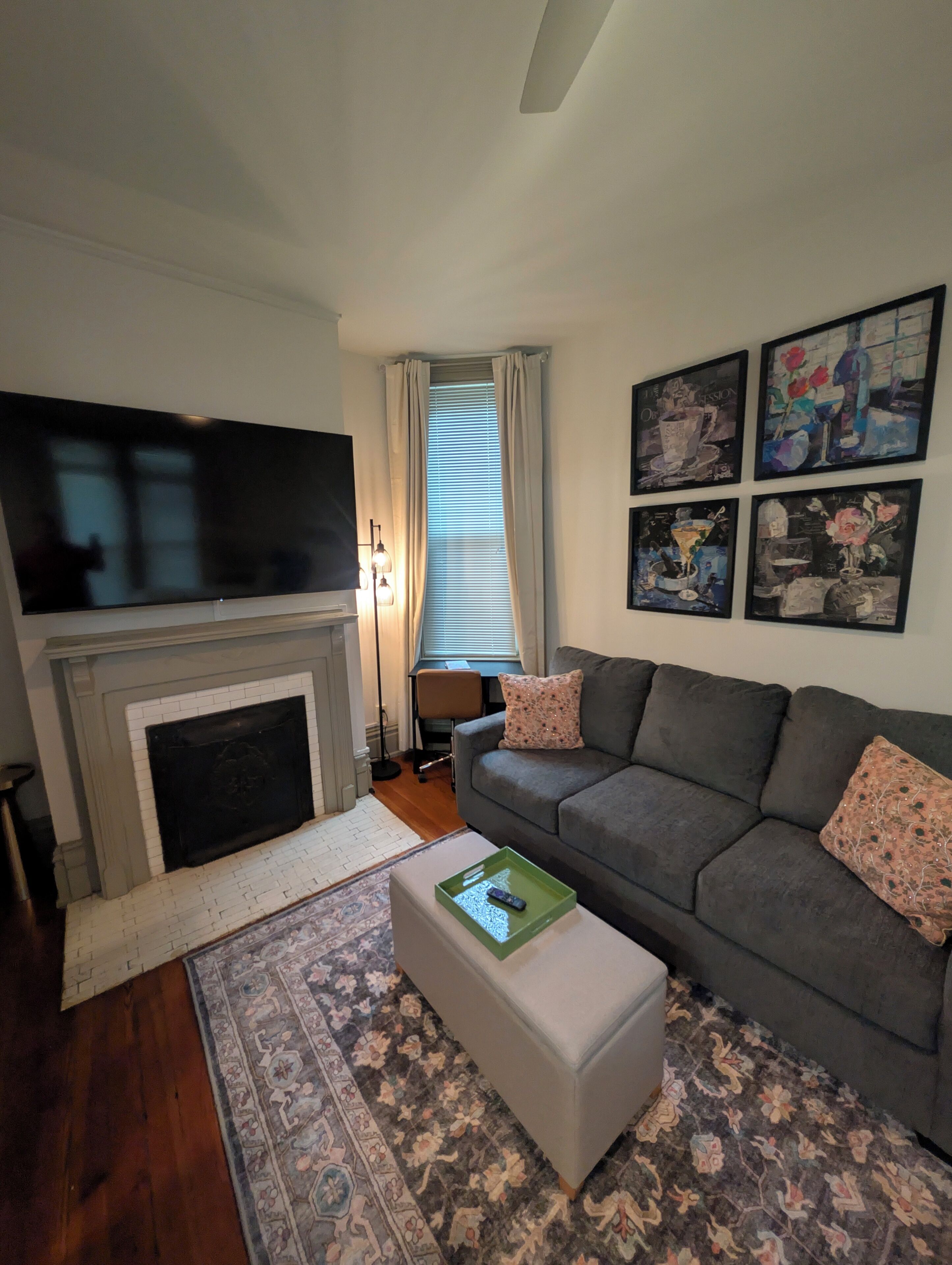 Una sala de estar con chimenea, un sofá, una mesa de centro, un televisor y obras de arte en la pared.