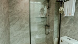 A modern bathroom with a glass-enclosed shower, a white toilet, and a towel rack.