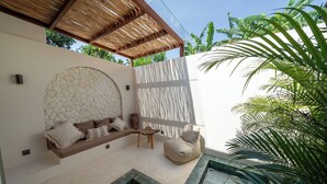 Un espacio al aire libre moderno con pared de piedra, banca de madera y una mesita.