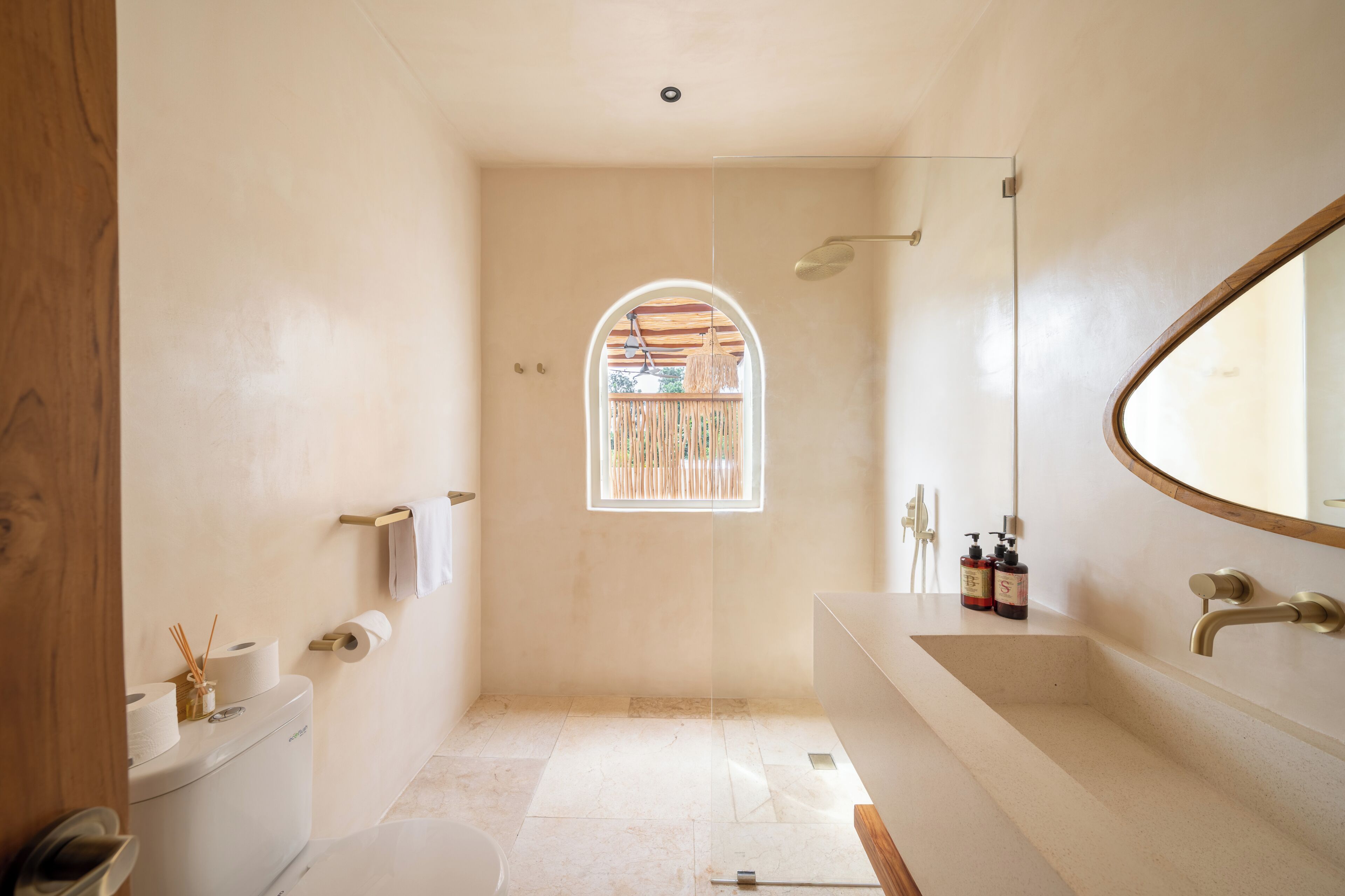 A bathroom with a toilet, a sink, a shower, and a window.