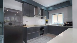 Una cucina moderna con mobili grigi, forno integrato e una grande finestra.