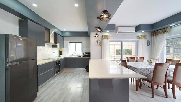 Una cucina moderna con mobili scuri, un'isola centrale e lampade a sospensione.