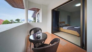Un balcone con tavolo e sedie, un letto con materasso e cuscini, e vista all'esterno.