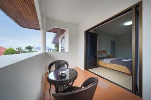 Un balcón con mesa y sillas, una cama con colchón y almohadas, y vistas al exterior.