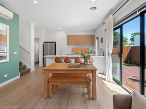 A modern kitchen with white cabinets, a built-in oven, and a stainless steel refrigerator. - Capel Haven House by Ready Set Stay (Capel Sound)
