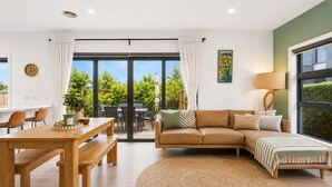 Una sala de estar moderna con un sofá, una mesa de comedor y un ventanal grande.