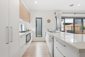 A modern kitchen with white cabinetry, a large window, and a view of the backyard. - Capel Haven House by Ready Set Stay (Capel Sound)