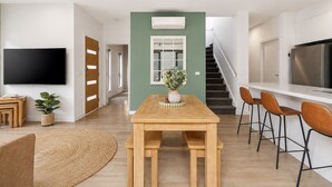 Un espacio habitable moderno con comedor, cocina y escalera.