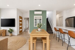 A modern living space with a dining area, kitchen, and a staircase. - Capel Haven House by Ready Set Stay (Capel Sound)