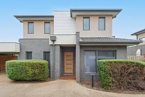 A two-story residential building with a modern design, featuring a flat roof, a front entrance with a wooden door, and a small front porch. - Capel Haven House by Ready Set Stay (Capel Sound)