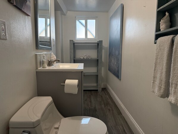A compact bathroom with a toilet, sink, and a small window. - Bring the family with lots of room only steps from the water in Mission Beach. (San Diego)