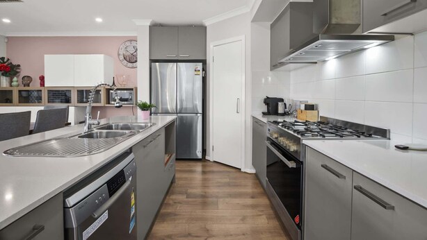 A modern kitchen with a stainless steel refrigerator, a built-in oven, and a gas stove. - Garden Retreat 4-Bed House in Tarneit (Tarneit)