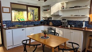 Cocina compacta con armarios blancos, una mesa de madera y sillas negras.