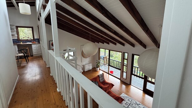 Un loft amplio con techo alto, vigas de madera, zona de cocina y ventanas grandes que ofrecen vistas al exterior.