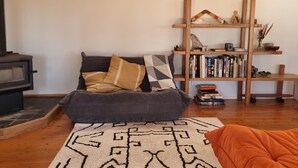 Una sala de estar acogedora con un sofá, una alfombra estampada, una estantería y una chimenea.