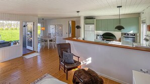 Een moderne keuken met een centraal eiland, een eethoek met tafel en stoelen, en een gezellige zithoek met een bank en een hond.