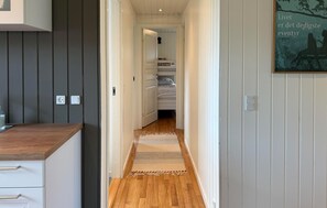 A narrow hallway with a wooden floor, a rug, a bed with white bedding, and a painting on the wall. - Amazing home in Dannemare with WiFi (Dannemare)