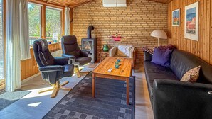 Een gezellige kamer met een open haard, leren stoelen, een bank en een houten tafel.