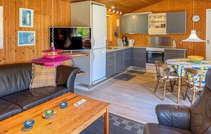 A cozy cabin interior with a living room, dining area, kitchen, and a large window. - Nice home in Rødby with WiFi (Rødby)