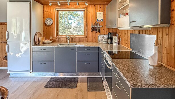 Een moderne keuken met houten lambrisering, een groot raam en een roestvrijstalen koelkast.