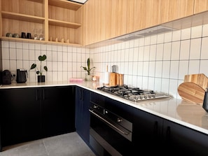 Una cucina moderna con mobili neri, un piano di lavoro bianco e uno schienale piastrellato.