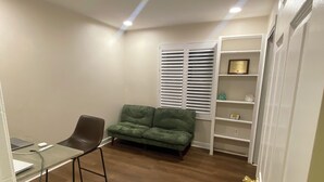 A room with a desk, chair, green sofa, and a white shelving unit. - 1-bedroom townhome in Odenton with guest share bath. (Odenton)