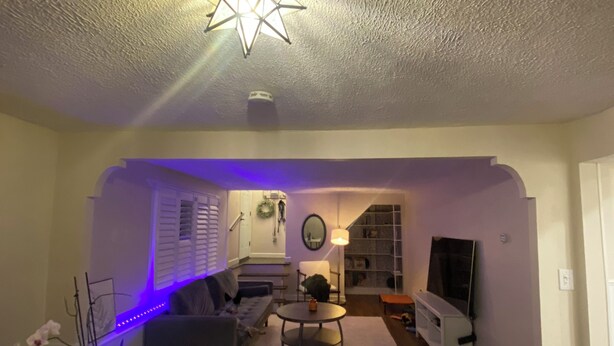 A living room with a star-shaped ceiling light, a sofa, a coffee table, and a TV. - 1-bedroom townhome in Odenton with guest share bath. (Odenton)