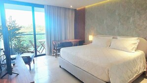 Een moderne hotelkamer met een groot bed, een bureau en uitzicht op groen.