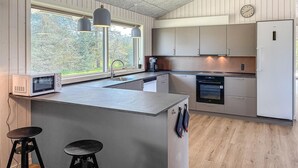 A modern kitchen with a central island, stainless steel appliances, and a large window providing a view of the outdoors. - Nice home in Oksbøl with WiFi (Oksbøl)