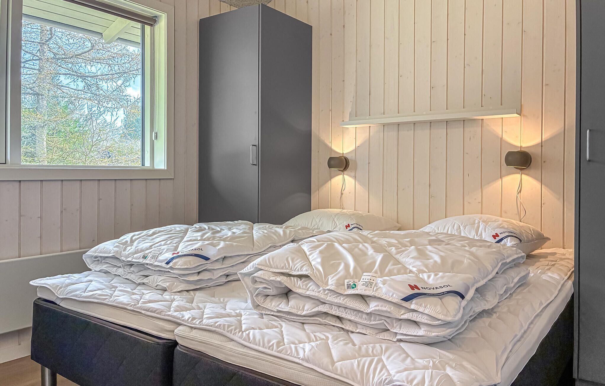 A bedroom with a bed, a wardrobe, and a window with a view of trees.