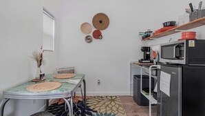 Eine kleine Küche mit Mikrowelle, Kaffeemaschine und Kühlschrank.
