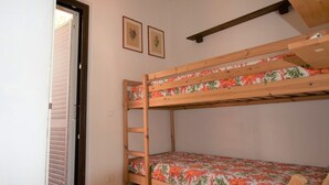 Ein Stockbett mit Blumenmuster-Bettwäsche, eine Holzleiter und zwei gerahmte Bilder an der Wand.