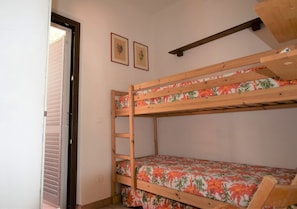 A bunk bed with floral bedding, a wooden ladder, and two framed pictures on the wall. - Beautiful equipped veranda (Fetovaia)