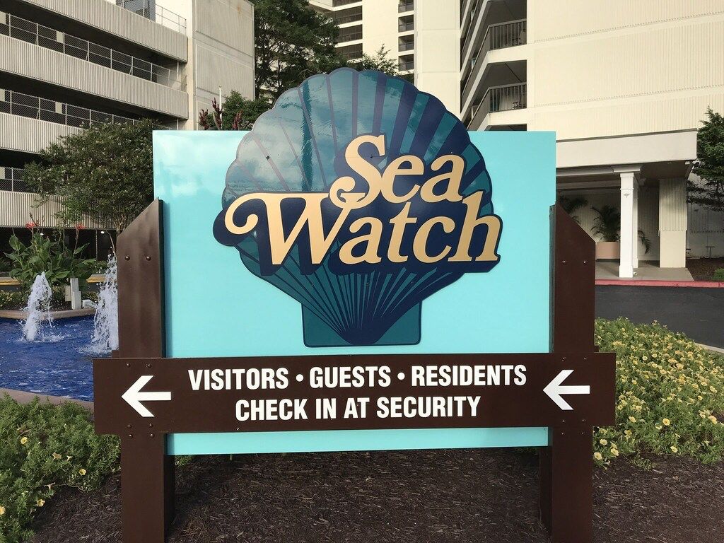 Un panneau indiquant « Sea Watch » et donnant des indications sur la direction à suivre pour accéder au service de sécurité, à destination des visiteurs, des clients et des résidents.
