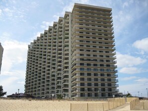 Un edificio de gran altura con varios balcones, fachada plana y cielo despejado al fondo.