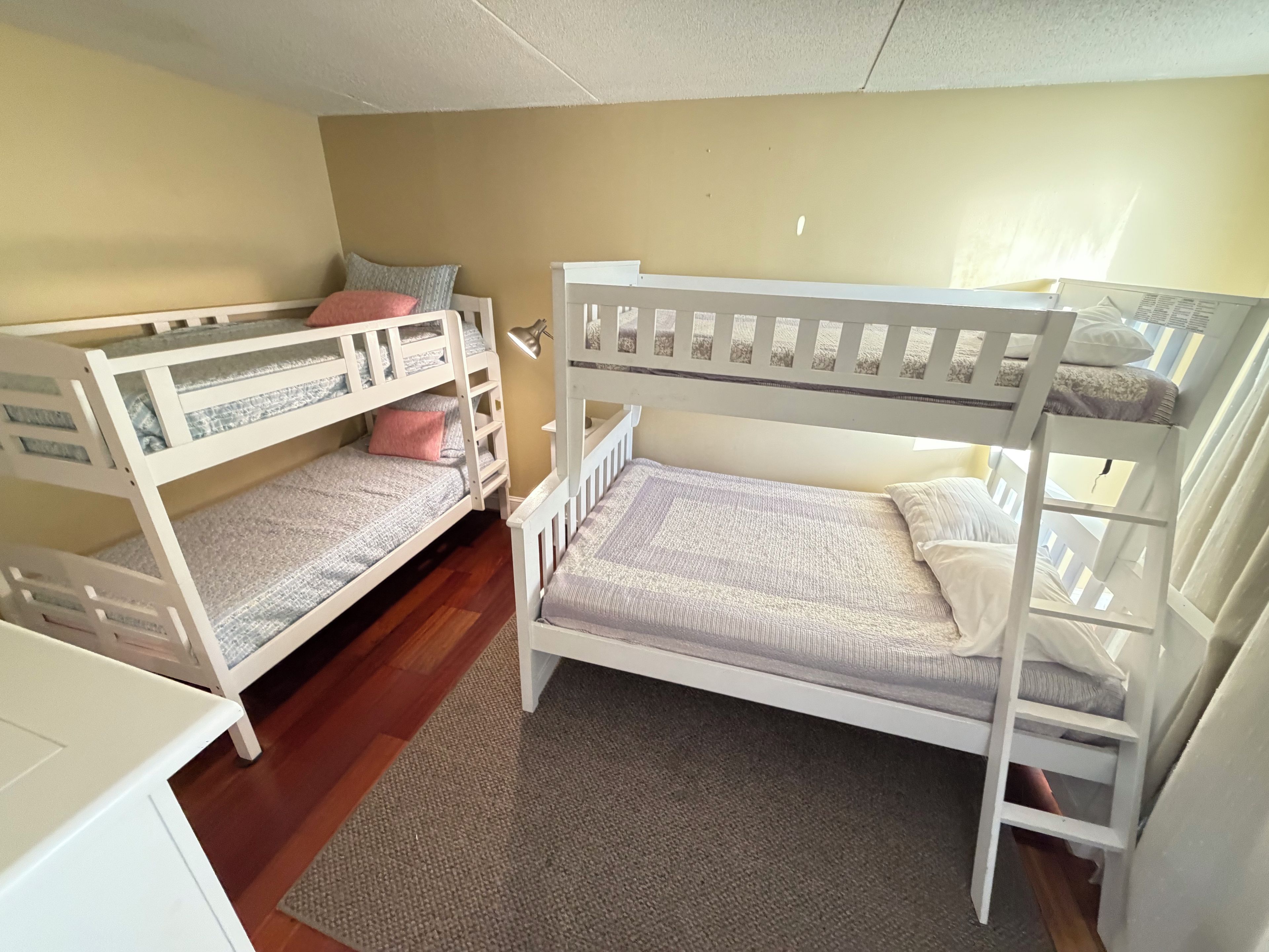 Habitació amb dos llits superposats, un escriptori petit i una finestra amb cortines.