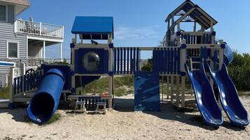 A beach playground with slides and a lemonade stand.