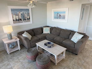A living room with a sectional sofa, a coffee table, a lamp, and two ottomans. - Oceanfront Spacious, 4 Bedroom Condo, Best Amenities & Views, Sleeps 12-14 (Ocean City)