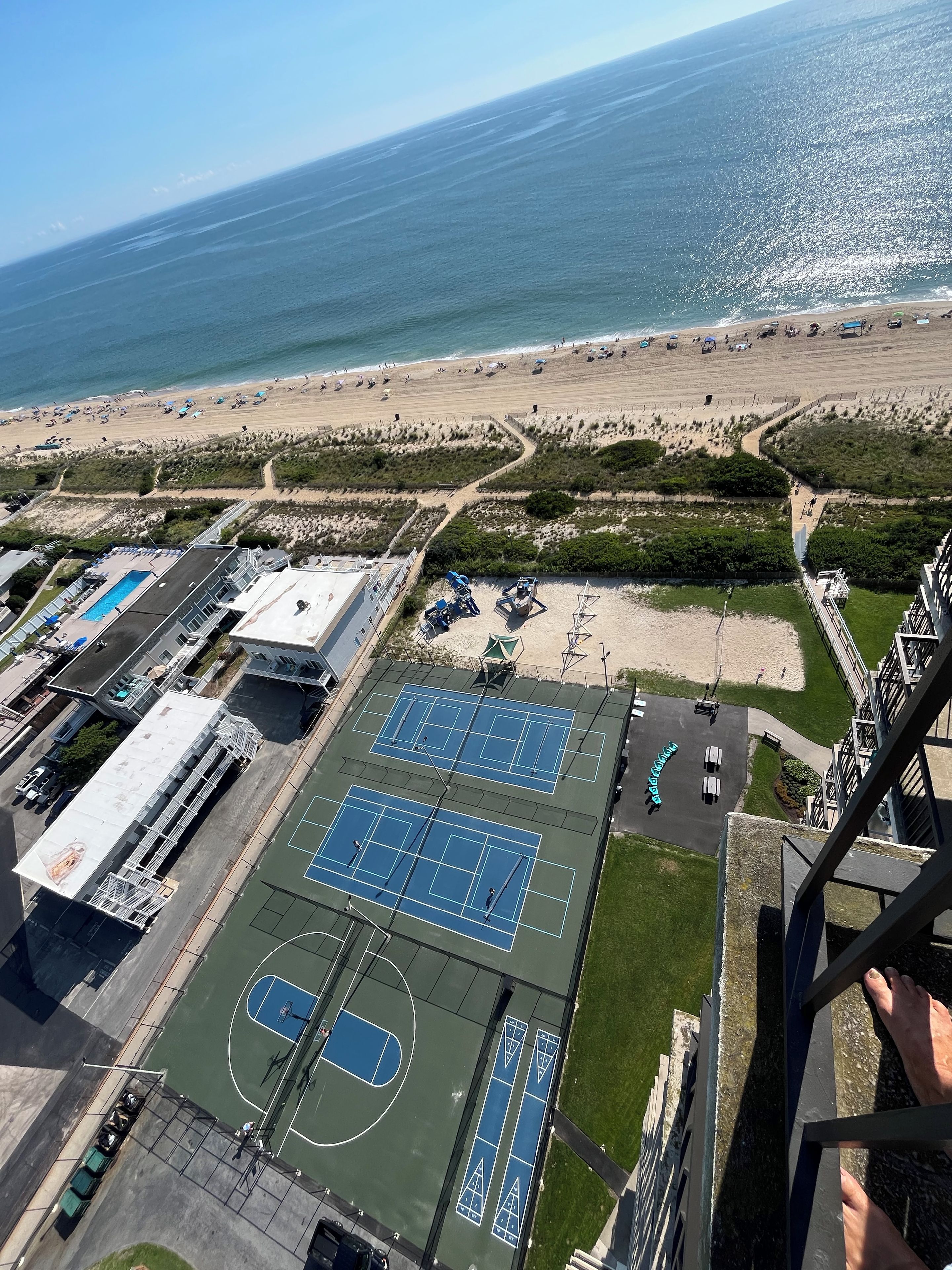 Vista aerea di una proprietà sul lungomare con campi da tennis, piscina e spiaggia.