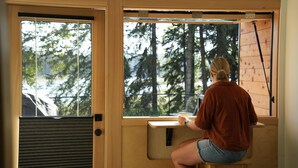 A person sitting at a wooden desk by a window with a view of trees.