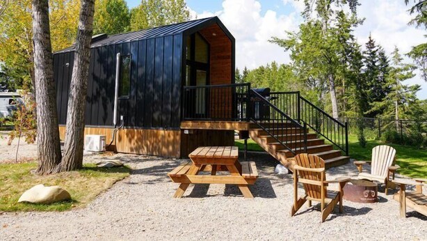 A cabin with a wooden deck, a staircase, and outdoor seating.