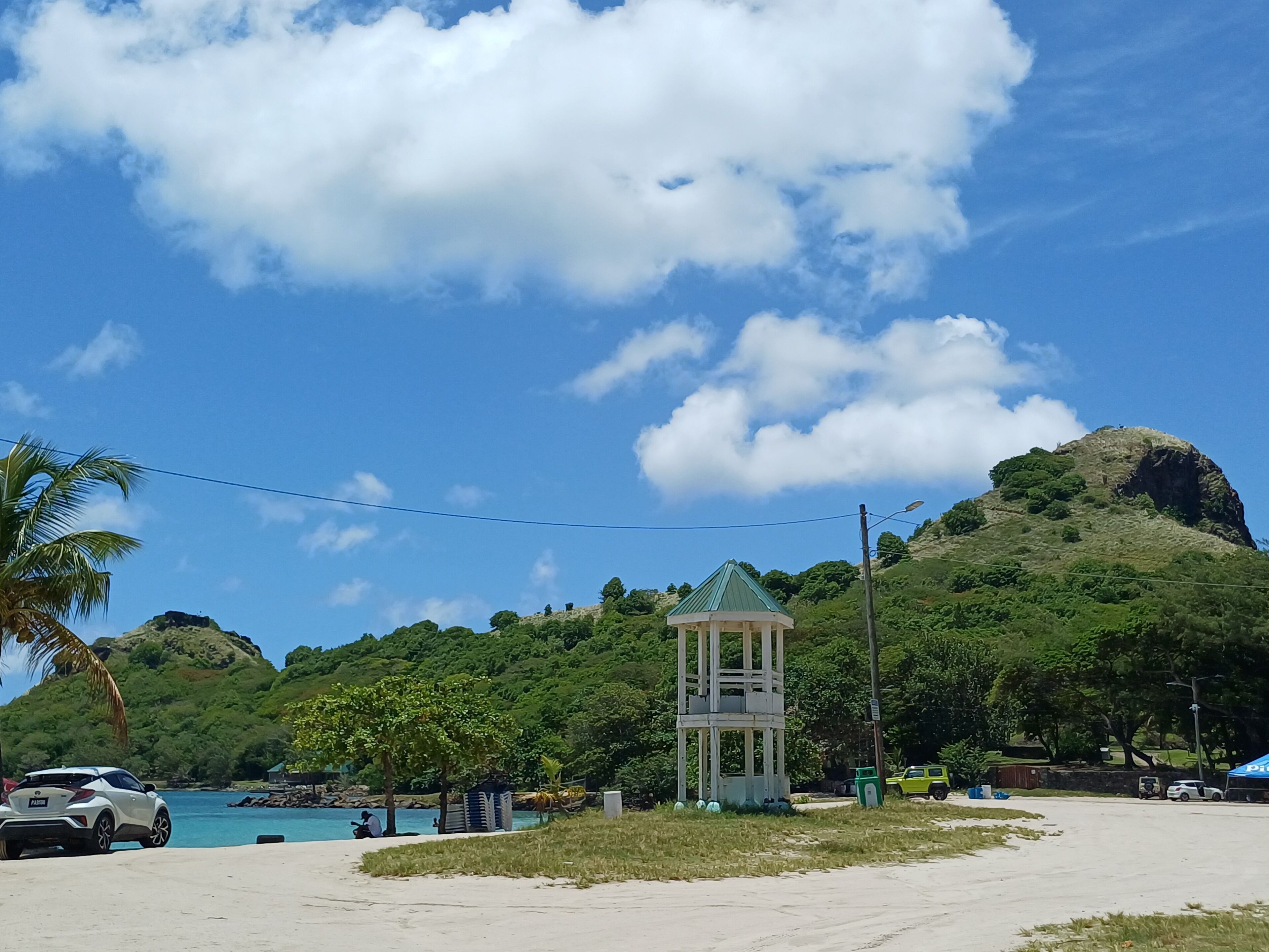 A beach with a small tower structure, clear skies, and a mountainous backdrop.